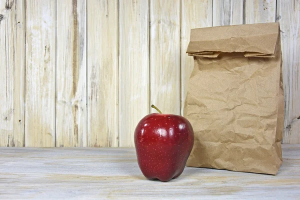 Κόκκινο μήλο με σακί μεσημεριανό καφέ χαρτί — Φωτογραφία Αρχείου