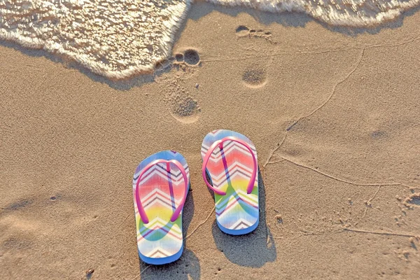 Flip flops och fotavtryck i beach sand — Stockfoto