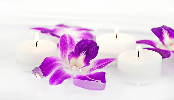 Flores de orquídea y velas en agua — Foto de Stock