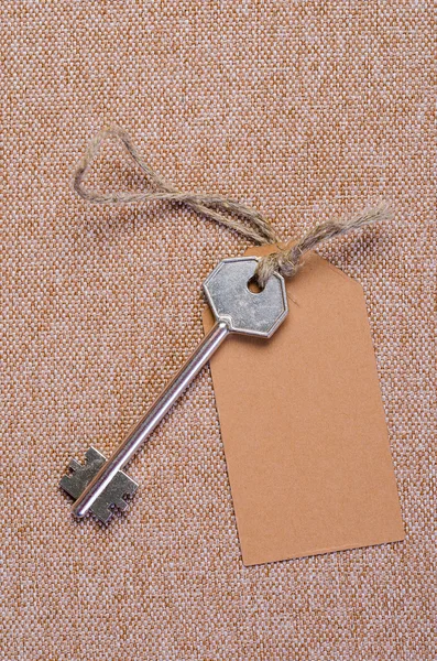 Paper tag attached to silver key — Stock Photo, Image