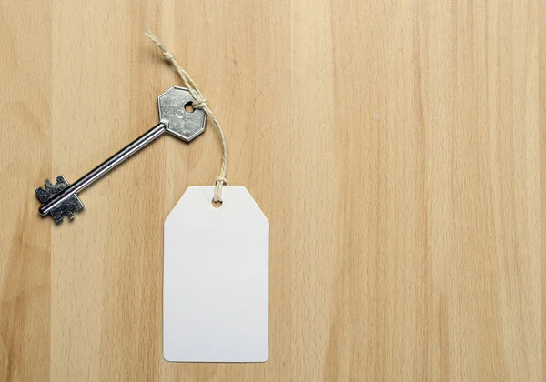 Paper tag attached to silver key — Stock Photo, Image