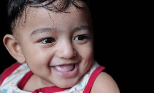 Een portret van een schattige indiaanse baby naar beneden en rechts kijkend met selectieve focus op het vooroog met kopieerruimte in zwarte achtergrond — Stockfoto