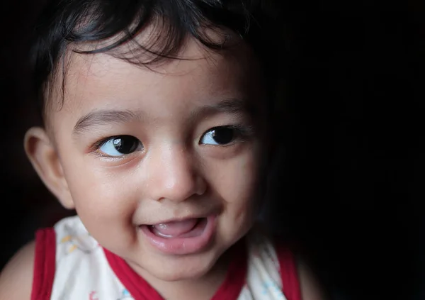 Портрет чарівної індійської дитини, яка дивиться праворуч з вибірковим фокусом на передньому оці з копіювальним простором на чорному тлі — стокове фото