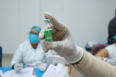 16 Ocak 2021, Kuganj, Bihar, Hindistan. MGM Tıp Fakültesi 'nde kovishield aşısını eldivenli elle sergileyen bir hemşire MGM 19' a karşı aşı hazırlığı yapıyor.