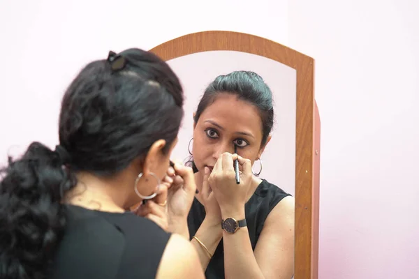 Een dame in de 30 zet leye liner make-up voor een spiegel — Stockfoto