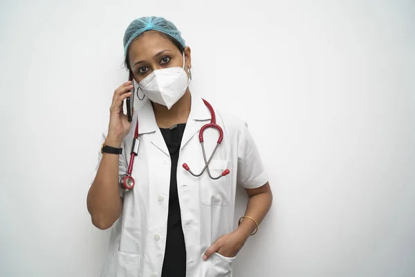 Un medico femminile indiano del sud negli anni '30 che parla di cellulare in cappotto bianco e stetoscopio rosso su sfondo bianco. — Foto Stock