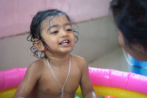 印度男婴在一个充气游泳池里洗澡 里面有泼洒水和漂浮的玩具 — 图库照片