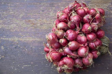 Ahşap zemine kurumuş Shallot (Allium ascalonicum) sürüsü yerleştirilmiş. Kırmızımsı-mor, ince ciltliler ve birkaç katmanları var. İçindeki et beyaz. Shallotlar birçok önemli besin içerir..