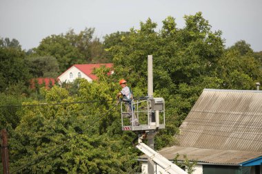 Elektrikçi yüksek voltajlı elektrik hatlarını tamir eder. Şehirdeki elektrik direkleri üzerine çalışma teknolojisi. Elektrik ile yükseklikte çalışma için güvenlik önlemleri