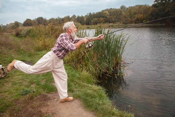 楽しそうに湖で釣りをしている髭の老人の全長ショット — ストック写真
