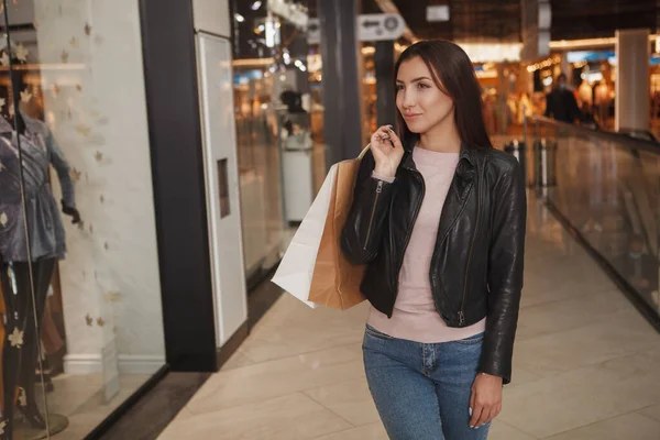 衣料品店の小売ディスプレイを見ながらショッピングバッグを運ぶゴージャス若い女性 — ストック写真