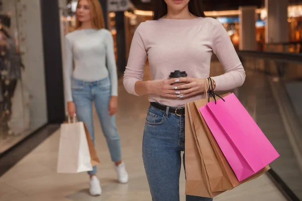 作物のショットの認識できない女性を保持するコーヒーやショッピングバッグ 彼女の友人が背景に歩いて — ストック写真