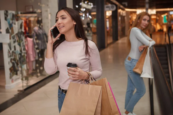 ショッピングモールを歩いている間に電話で話している陽気な女性 — ストック写真