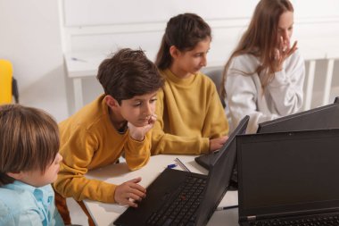 Bilgisayar okulunda laptoplar üzerinde çalışan bir grup çocuk.