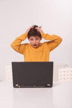 Küçük bir çocuğun şok olmuş bir şekilde dizüstü bilgisayarının önünde dikey görüntüsü.