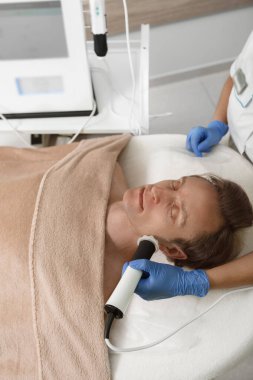 Olgun bir adamın güzellik salonunda yüz bakımı sırasında dinlenirken çekilmiş dikey bir fotoğrafı.