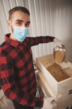Bira fabrikasında çalışan, tıbbi maske takan profesyonel bir bira üreticisi.