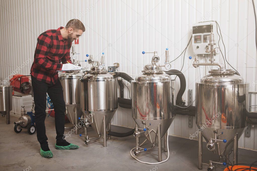 Full length shot of a brewer checking beer tanks at his microbrewery, copy space