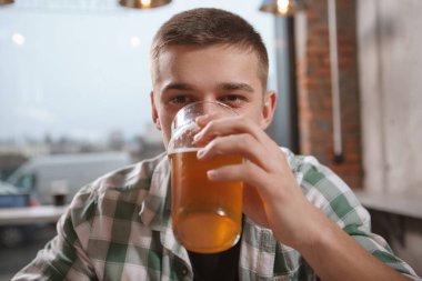 Bir adamın elindeki bira bardağına odaklan, barda iç.