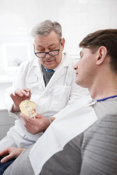 一名老年男性牙科医生与病人交谈的垂直镜头 — 图库照片