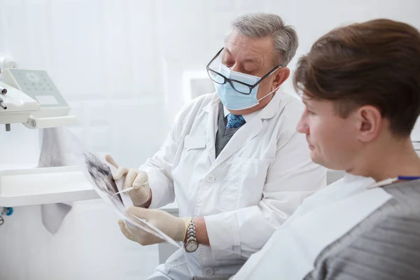 男病人和他的牙医在预约牙医时检查下巴X光扫描 — 图库照片