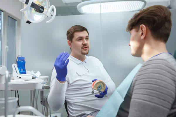 Młody Dentysta Pracujący Klinice Rozmawiający Pacjentem — Zdjęcie stockowe