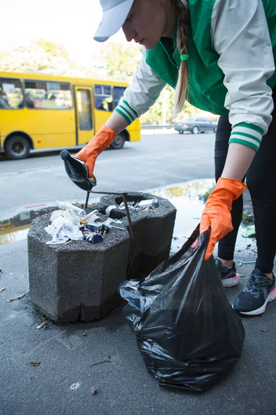一名女性积极分子在城市街道上捡垃圾时被垂直截击 — 图库照片