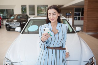 Galeride akıllı telefon kullanan neşeli, güzel bir kadın.