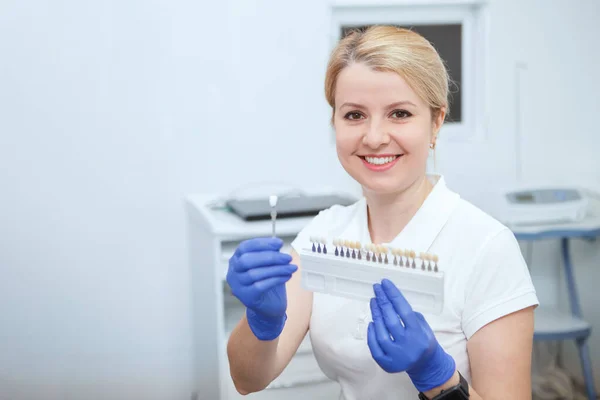 Charmig Kvinnlig Tandläkare Ler Mot Kameran Håller Tandblekning Skugga Diagram — Stockfoto