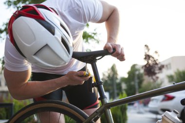 Bisiklet kasklı tanınmaz bisikletçi bisiklet koltuğunu tamir ediyor.