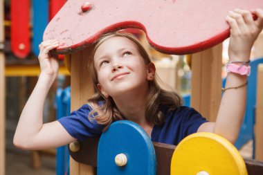 Güzel, mutlu bir kız dışarıda oyun bahçesinde yaz gününün tadını çıkarıyor.