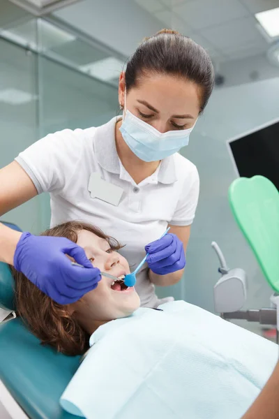 Vertikální Záběr Zubařky Pracující Klinice Léčící Zuby Mladého Chlapce — Stock fotografie