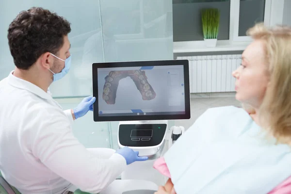 Dentist and patient looking at dental scan on the screen of computer