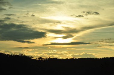 Güneş sık bir ormanın arkasında batıyor ve ardından dağlar geliyor..