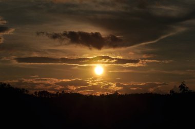 Güneş sık bir ormanın arkasında batıyor ve ardından dağlar geliyor..