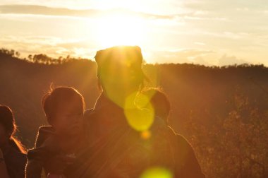 Güneş sık bir ormanın arkasında batıyor ve ardından dağlar geliyor..