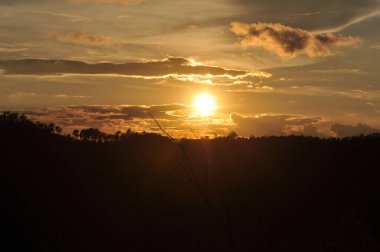Güneş sık bir ormanın arkasında batıyor ve ardından dağlar geliyor..