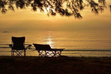 Gün batımında deniz kıyısında güneşli yataklar