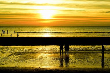 Gün batımında sahilde bir çiftin silueti.