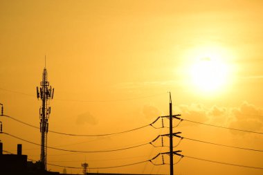 Günbatımı manzarası büyük şehirlerde güzel altın sarısı gökyüzü, gökyüzü ve parlak günlerdeki güzel bulutlarla elektrik iletim sistemi.