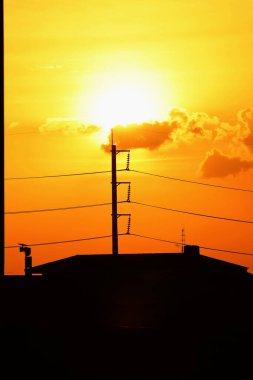 Günbatımı manzarası büyük şehirlerde güzel altın sarısı gökyüzü, gökyüzü ve parlak günlerdeki güzel bulutlarla elektrik iletim sistemi.