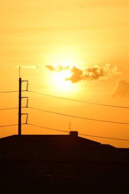 Günbatımı manzarası büyük şehirlerde güzel altın sarısı gökyüzü, gökyüzü ve parlak günlerdeki güzel bulutlarla elektrik iletim sistemi.