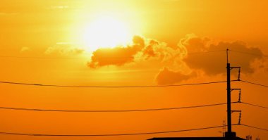 Günbatımı manzarası büyük şehirlerde güzel altın sarısı gökyüzü, gökyüzü ve parlak günlerdeki güzel bulutlarla elektrik iletim sistemi.
