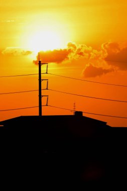 Günbatımı manzarası büyük şehirlerde güzel altın sarısı gökyüzü, gökyüzü ve parlak günlerdeki güzel bulutlarla elektrik iletim sistemi.
