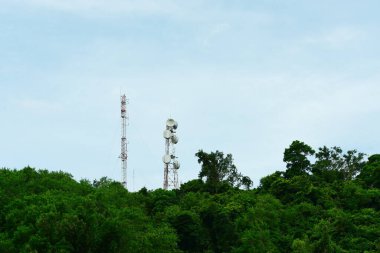 Yeşil ormanda antenleri olan yüksek voltajlı kuleler.
