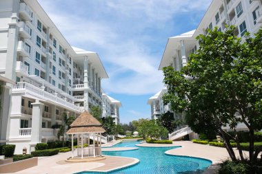 Güzel yüzme havuzu ve aydınlık bir günde gökyüzü manzaralı güzel bir bina..