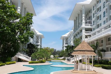 Güzel yüzme havuzu ve aydınlık bir günde gökyüzü manzaralı güzel bir bina..