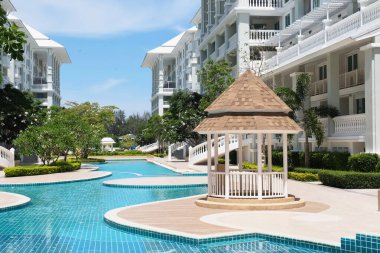 Güzel yüzme havuzu ve aydınlık bir günde gökyüzü manzaralı güzel bir bina..