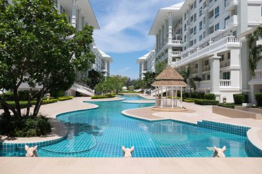 Güzel yüzme havuzu ve aydınlık bir günde gökyüzü manzaralı güzel bir bina..