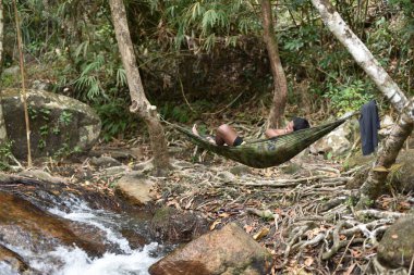 Hamakta yatan adam dağ nehrinin üzerinde